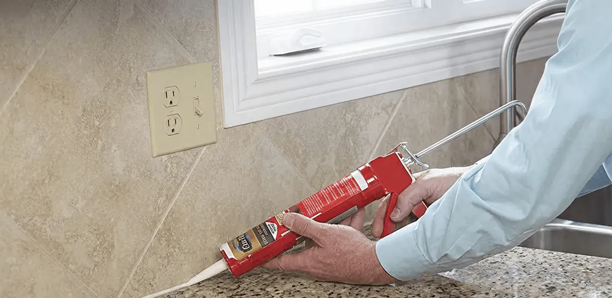 Handyman applying caulk along a kitchen backsplash and countertop seam in Springfield, MO